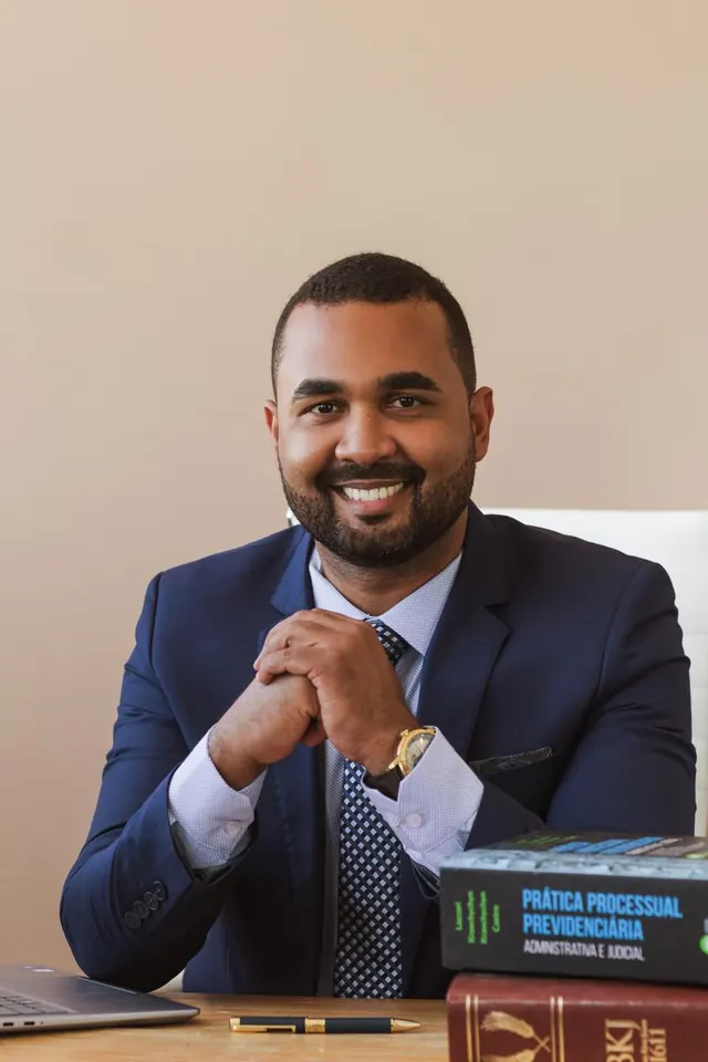 Ronicleiton Martins sentado à mesa de trabalho com livros jurídicos